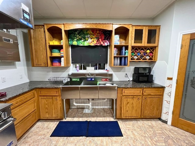 kitchen with range, dark stone counters, light tile flooring, and a drop ceiling