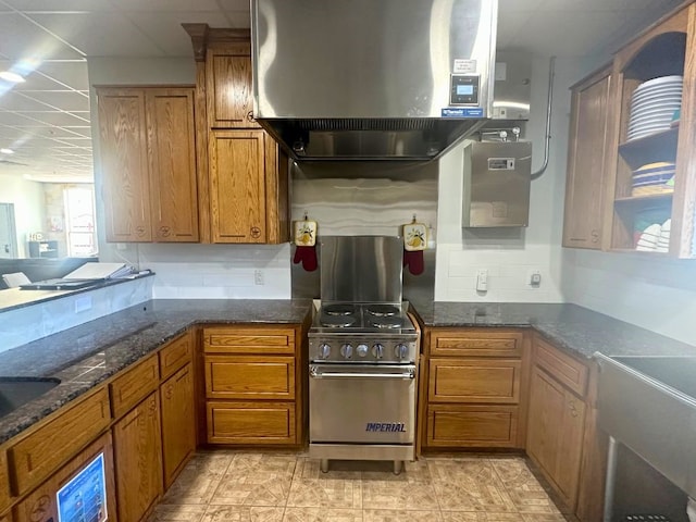 kitchen featuring dark stone counters, extractor fan, high end range, light tile floors, and sink