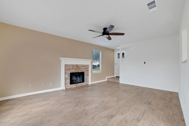 unfurnished living room with ceiling fan, a fireplace, and light wood-type flooring