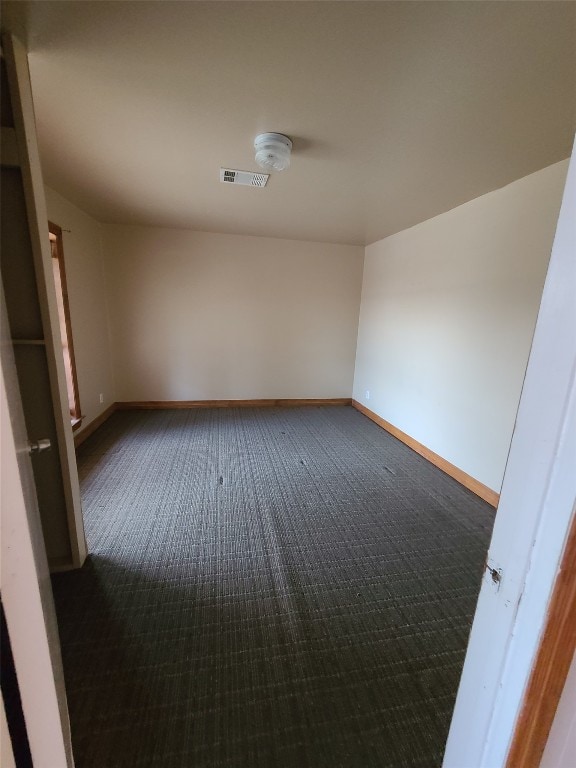 spare room featuring dark carpet