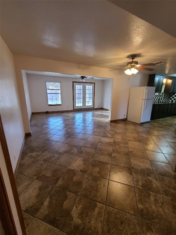 tiled empty room with french doors, ceiling fan, and a textured ceiling