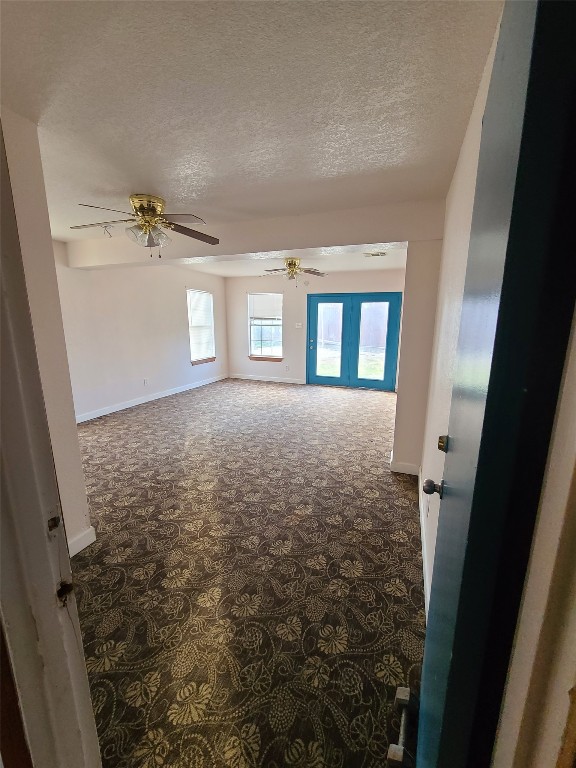 carpeted empty room featuring french doors, ceiling fan, and a textured ceiling