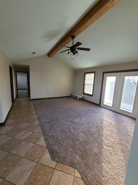 carpeted spare room featuring ceiling fan, lofted ceiling with beams, and french doors