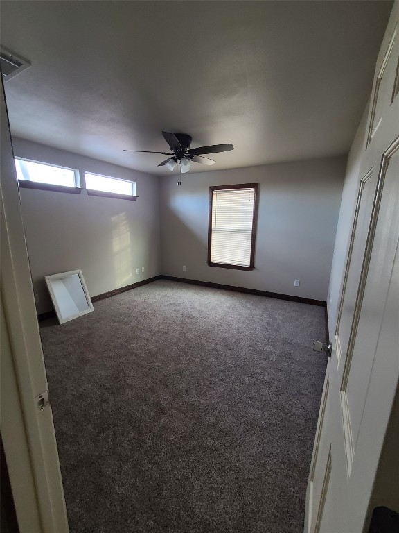 unfurnished room with ceiling fan and dark carpet