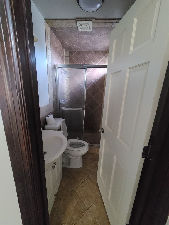 bathroom with a shower with shower door, tile flooring, vanity, and toilet