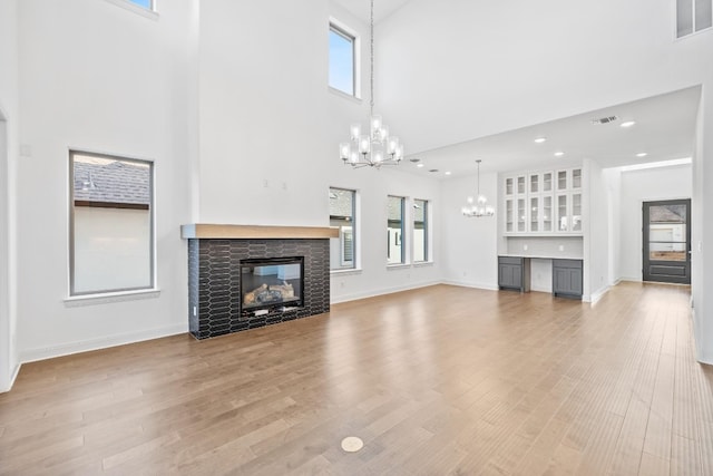 unfurnished living room featuring plenty of natural light, a towering ceiling, and hardwood / wood-style flooring