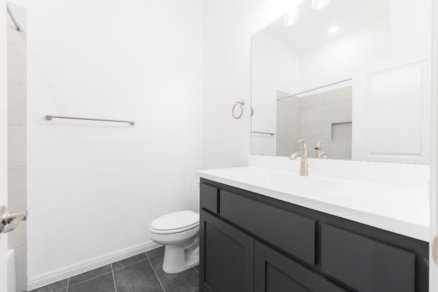 bathroom featuring tile patterned floors, vanity, a tile shower, and toilet