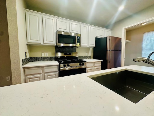 kitchen with white cabinetry, sink, lofted ceiling, and appliances with stainless steel finishes