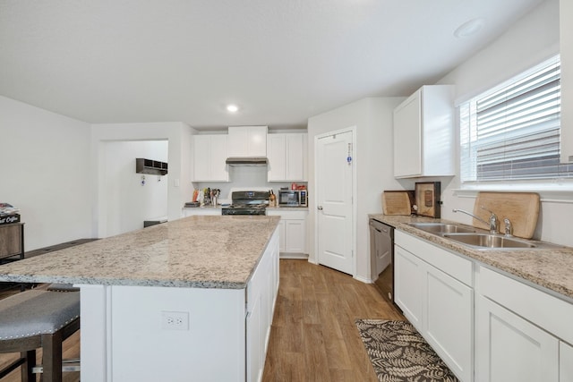 kitchen with sink, light wood-type flooring, a kitchen island, white cabinetry, and stainless steel appliances