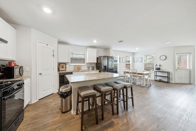 kitchen featuring white cabinets, a kitchen island, stainless steel appliances, and light wood-type flooring