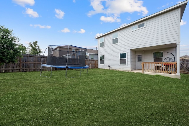 rear view of house with a yard, a trampoline, and a patio