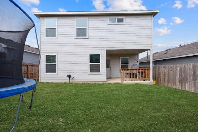 back of house featuring a lawn, a patio area, and a trampoline