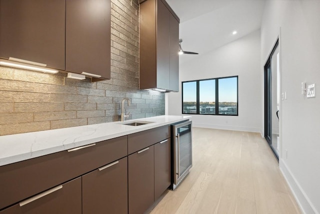 18116 Cedar Sage Ct, Lago Vista, TX 78645 - kitchen with wine cooler, tasteful backsplash, light stone countertops, light wood-style flooring, and a sink