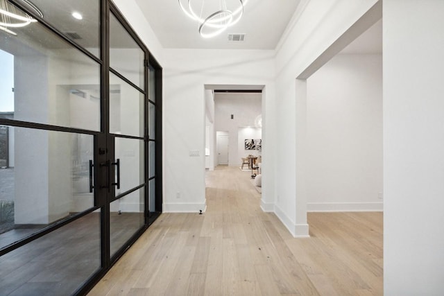 hallway featuring a chandelier, french doors, and light hardwood / wood-style flooring