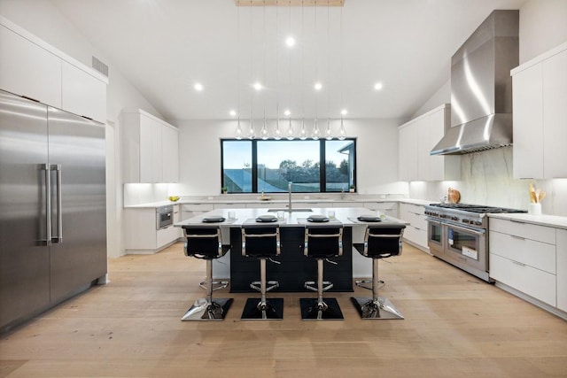18116 Cedar Sage Ct, Lago Vista, TX 78645 - kitchen with high quality appliances, wall chimney exhaust hood, light countertops, a kitchen island with sink, and white cabinets