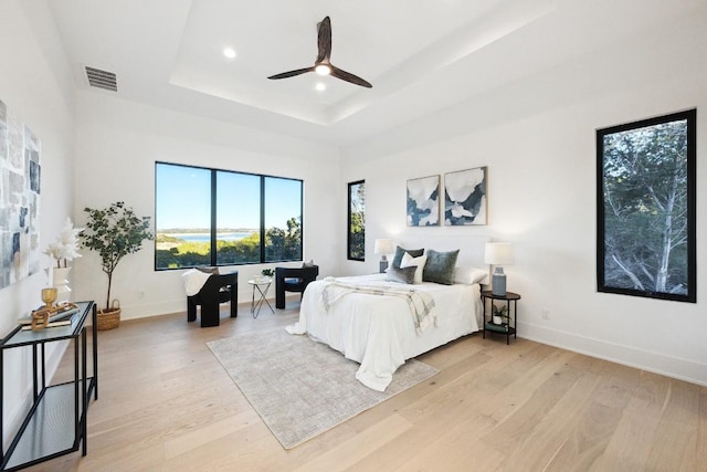 bedroom with a tray ceiling, ceiling fan, and light hardwood / wood-style floors