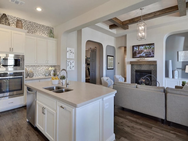 kitchen featuring white cabinets, beamed ceiling, appliances with stainless steel finishes, and dark hardwood / wood-style floors