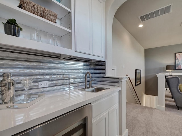 kitchen featuring sink, carpet floors, white cabinets, and tasteful backsplash