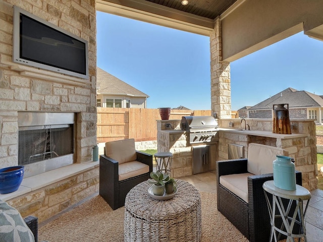 view of terrace with area for grilling, sink, and an outdoor stone fireplace