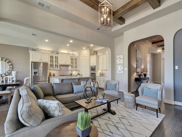 living room featuring beamed ceiling, hardwood / wood-style floors, and a chandelier