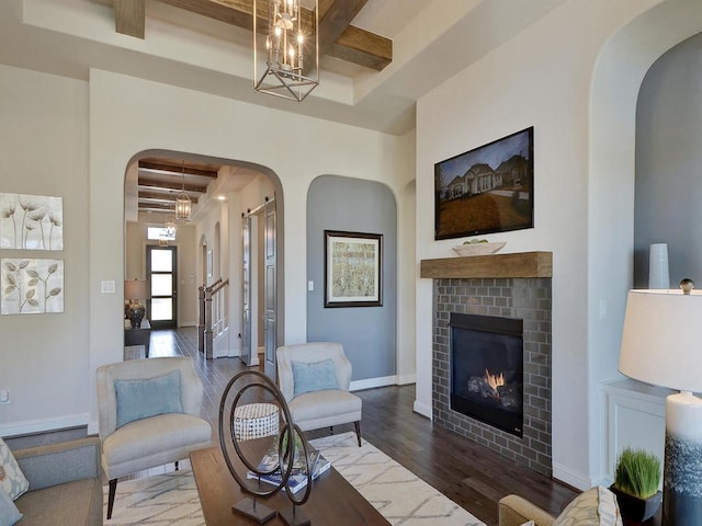 living room with dark wood-type flooring, a fireplace, beamed ceiling, coffered ceiling, and a raised ceiling