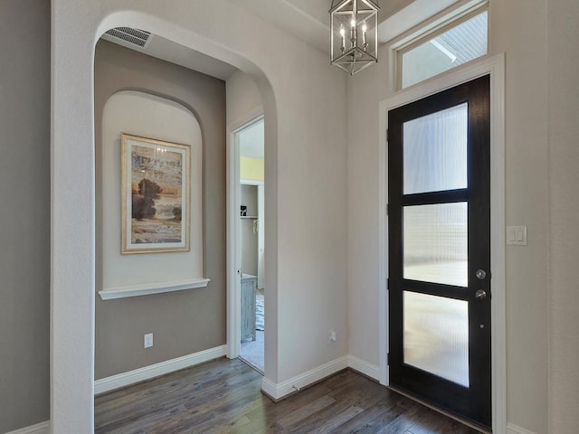 foyer entrance with a healthy amount of sunlight, a notable chandelier, and dark hardwood / wood-style flooring