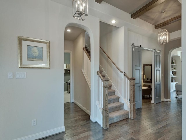 foyer entrance featuring beamed ceiling, a barn door, and dark wood-type flooring