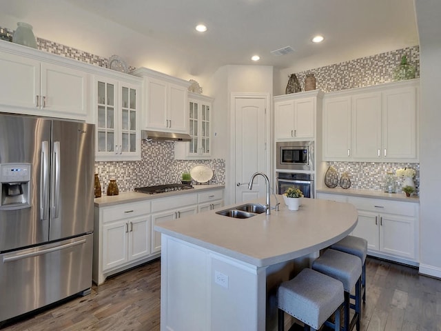 kitchen with dark hardwood / wood-style floors, tasteful backsplash, an island with sink, appliances with stainless steel finishes, and sink