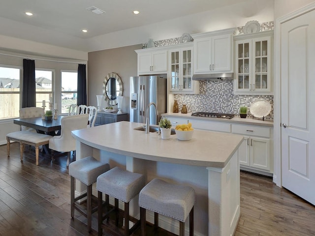 kitchen with white cabinets, backsplash, a kitchen island with sink, dark wood-type flooring, and appliances with stainless steel finishes