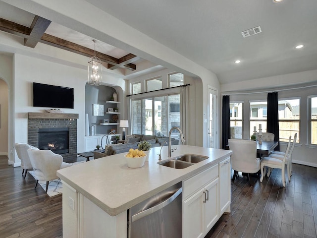 kitchen featuring beamed ceiling, a center island with sink, dark hardwood / wood-style flooring, and a fireplace