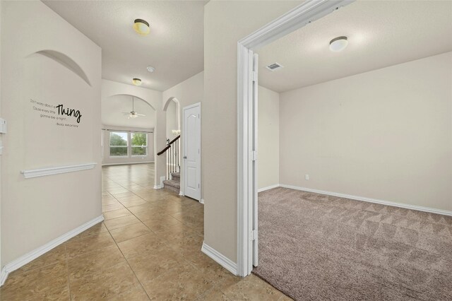 hallway featuring light colored carpet and a textured ceiling