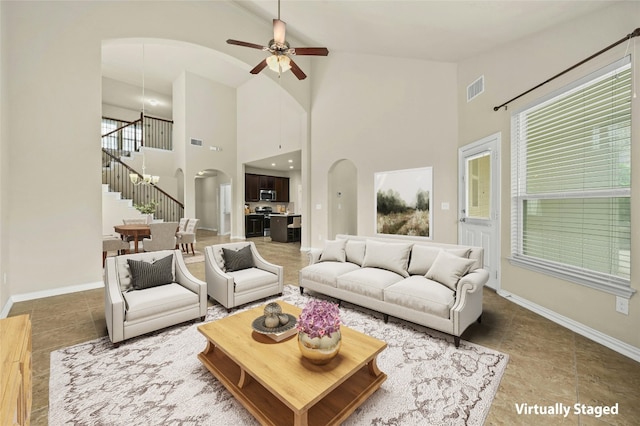 tiled living room with ceiling fan, plenty of natural light, and a towering ceiling