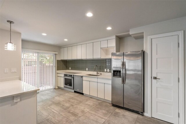 kitchen featuring tasteful backsplash, pendant lighting, sink, white cabinets, and appliances with stainless steel finishes