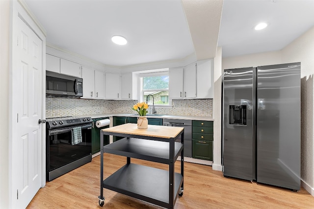 kitchen featuring sink, backsplash, white cabinetry, stainless steel appliances, and light hardwood / wood-style flooring