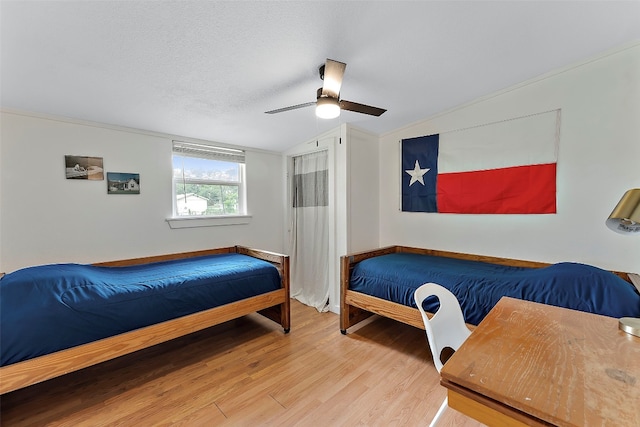 bedroom with wood-type flooring, ornamental molding, vaulted ceiling, a textured ceiling, and ceiling fan