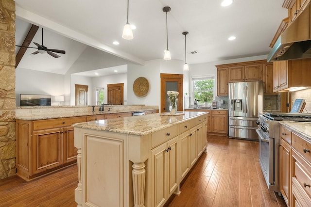 1451 Gatlin Creek Rd E, Driftwood, TX 78619 - kitchen with appliances with stainless steel finishes, vaulted ceiling with beams, a kitchen island, decorative light fixtures, and tasteful backsplash