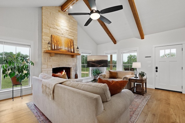 1451 Gatlin Creek Rd E, Driftwood, TX 78619 - living room with light wood-type flooring, a healthy amount of sunlight, beamed ceiling, and a stone fireplace