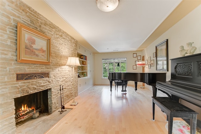 misc room with a fireplace, built in shelves, light hardwood / wood-style flooring, and ornamental molding