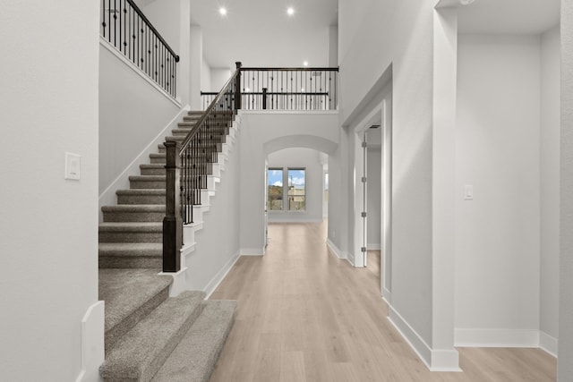 entrance foyer with a towering ceiling and light hardwood / wood-style flooring