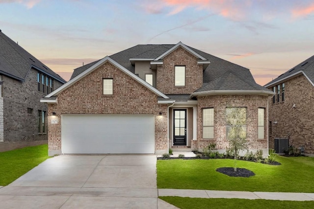 view of front of home featuring central AC unit, a garage, and a yard