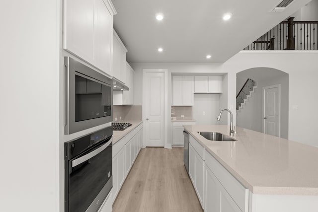 kitchen featuring sink, white cabinetry, appliances with stainless steel finishes, and a center island with sink