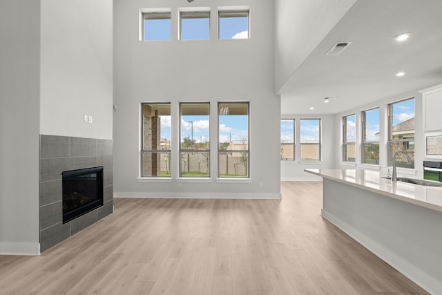 unfurnished living room with sink, light hardwood / wood-style flooring, and a tile fireplace