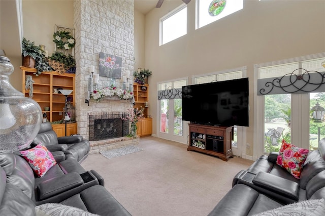 carpeted living room featuring a fireplace, a towering ceiling, and a healthy amount of sunlight