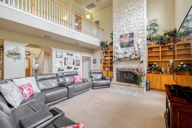 carpeted living room featuring a towering ceiling and a brick fireplace