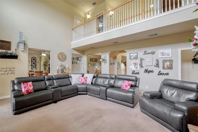 carpeted living room featuring ceiling fan and a high ceiling