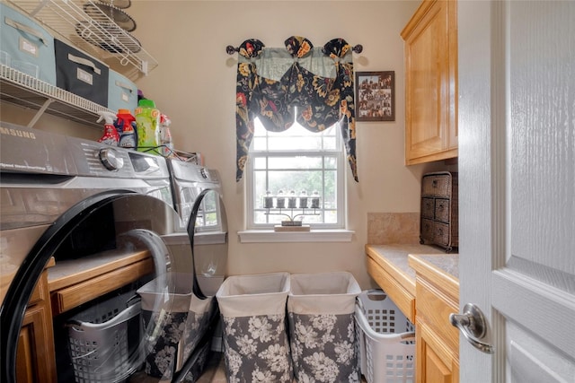 clothes washing area with cabinets and washing machine and clothes dryer