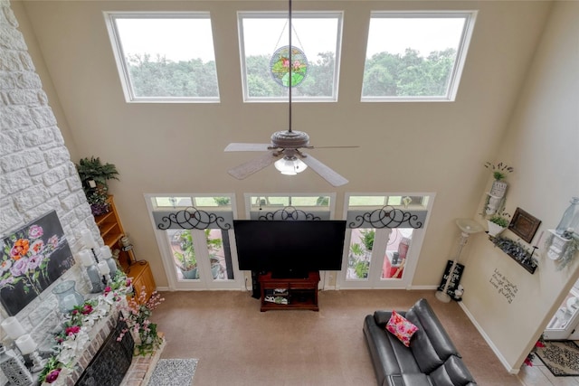 carpeted living room with ceiling fan and a high ceiling