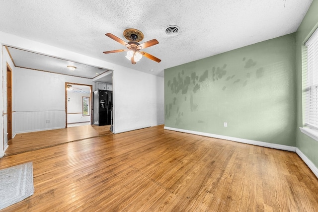 spare room featuring a wealth of natural light, ceiling fan, a textured ceiling, and light wood-type flooring