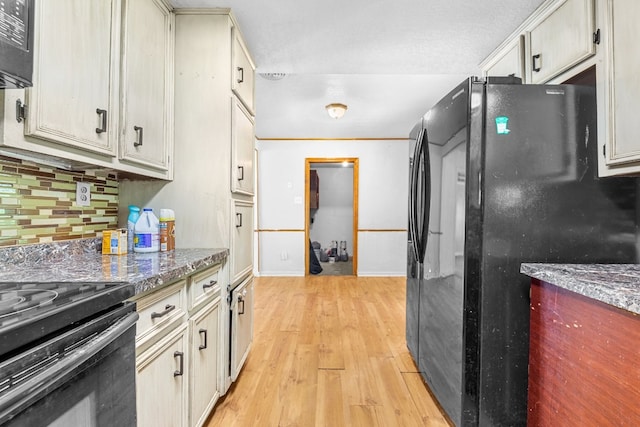 kitchen featuring light stone countertops, black appliances, light hardwood / wood-style floors, and tasteful backsplash