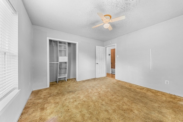 unfurnished bedroom featuring ceiling fan, a closet, a textured ceiling, and light colored carpet